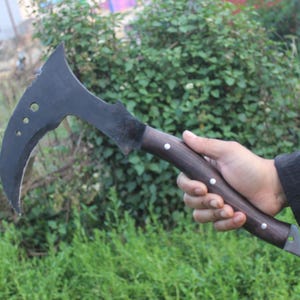 May include: A black curved blade with a wooden handle. The blade has a sharp point and a curved edge. The handle is made of wood and has a dark brown finish.