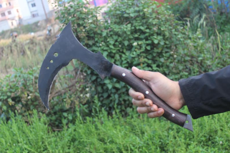 May include: A black curved blade with a wooden handle. The blade has a sharp point and a curved edge. The handle is made of wood and has a dark brown finish.