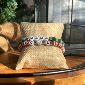 May include: Two colorful beaded bracelets with white letter beads spelling out "MAMA CJ L".
