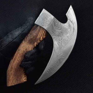 May include: A silver axe with a wooden handle. The axe head is curved and features an intricate design of a wolf's head and runes. The handle is made of wood with a dark brown stain.