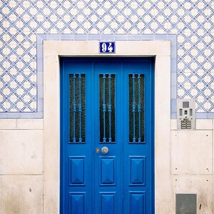 May include: A blue double door with a number "94" above it. The door has a decorative pattern and is set in a white frame. The door is surrounded by white and blue patterned tiles.