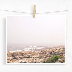 May include: A misty seascape with a rocky coastline and ocean waves crashing against the shore.