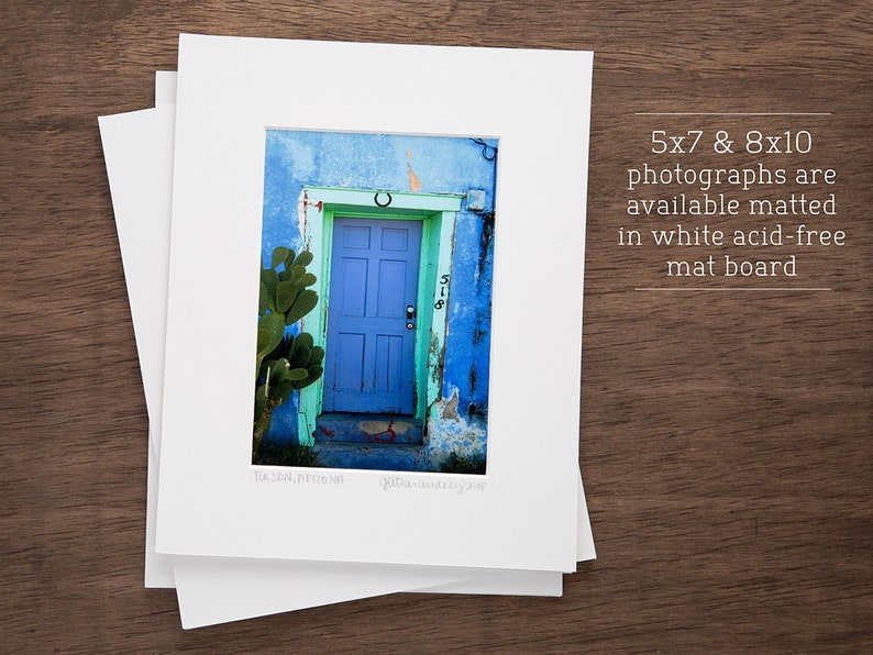 May include: A photograph of a blue door with a horseshoe above it. The door is surrounded by a green cactus and a blue wall. The door has a number "518" on it. The photograph is matted in white acid-free mat board and is available in 5x7 and 8x10 sizes.