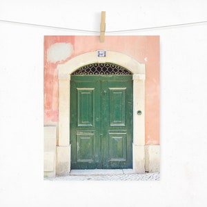 May include: A green double door with a metal grate above it, set in a peach-coloured wall with a white trim. The door has a number "25" above it.