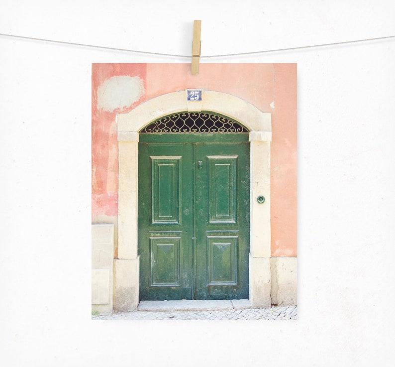 May include: A green double door with a metal grate above it, set in a peach-coloured wall with a white trim. The door has a number "25" above it.