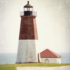 May include: A white and red brick lighthouse with a black lantern room and a smaller white building with a red roof in the foreground.