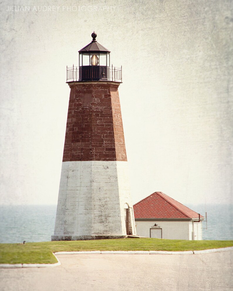 May include: A white and red brick lighthouse with a black lantern room and a smaller white building with a red roof in the foreground.