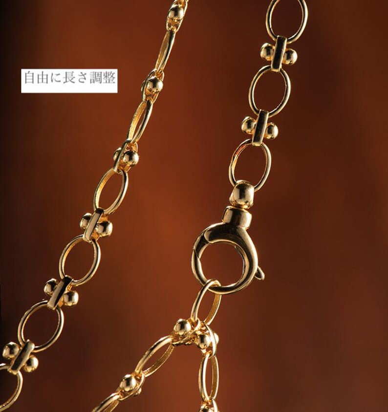 May include: A gold chain necklace with a lobster clasp closure. The chain is made of oval links with small round beads at each link.