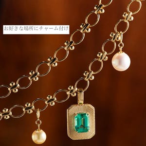 May include: A gold chain necklace with three charms: a green emerald gemstone pendant, a white pearl, and a smaller white pearl. The chain is made of interlocking circles with small beads between each circle.