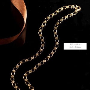 May include: A gold chain necklace with a delicate, linked design. The chain is 45cm long and 5.3mm wide.