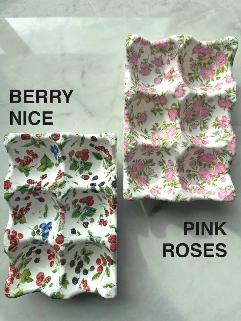 Peut inclure: Deux plateaux &agrave; &oelig;ufs rectangulaires en c&eacute;ramique avec six alv&eacute;oles chacun. Le plateau de gauche pr&eacute;sente un motif color&eacute; de fraises rouges, de m&ucirc;res et de groseilles rouges avec des feuilles vertes. Le plateau de droite affiche un motif de roses roses.