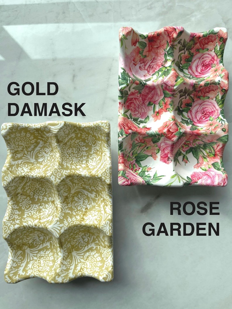 Peut inclure: Deux plateaux &agrave; &oelig;ufs rectangulaires avec six alv&eacute;oles chacun. L'un pr&eacute;sente un motif damass&eacute; dor&eacute; sur fond blanc, &eacute;tiquet&eacute; GOLD DAMASK. L'autre affiche un motif floral de roses roses et vertes, &eacute;tiquet&eacute; ROSE GARDEN.