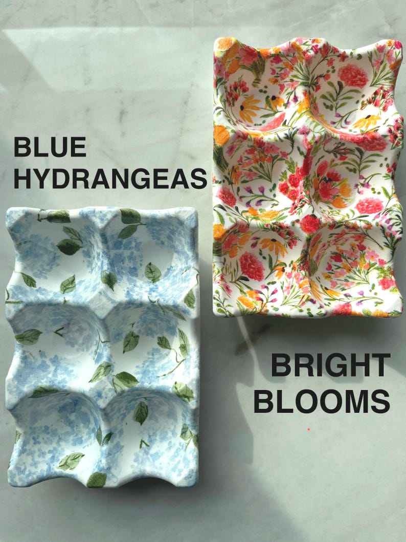 Peut inclure: Deux plateaux &agrave; &oelig;ufs rectangulaires en c&eacute;ramique avec six alv&eacute;oles chacun. Le plateau de gauche pr&eacute;sente un motif d'hortensias bleus avec des feuilles vertes, marqu&eacute; BLUE HYDRANGEAS. Le plateau de droite affiche un motif floral color&eacute;, marqu&eacute; BRIGHT BLOOMS.
