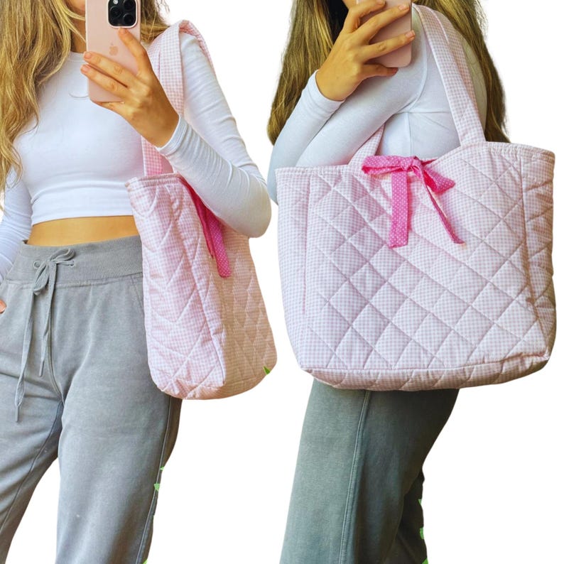 May include: A pink and white quilted tote bag with a pink bow. The bag has a gingham pattern and is made of a soft, quilted fabric.