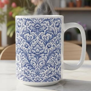 May include: White ceramic mug with a blue floral pattern. The mug has a large handle and is filled with a hot beverage, with steam rising from the top. The floral design is intricate and covers the entire surface of the mug.