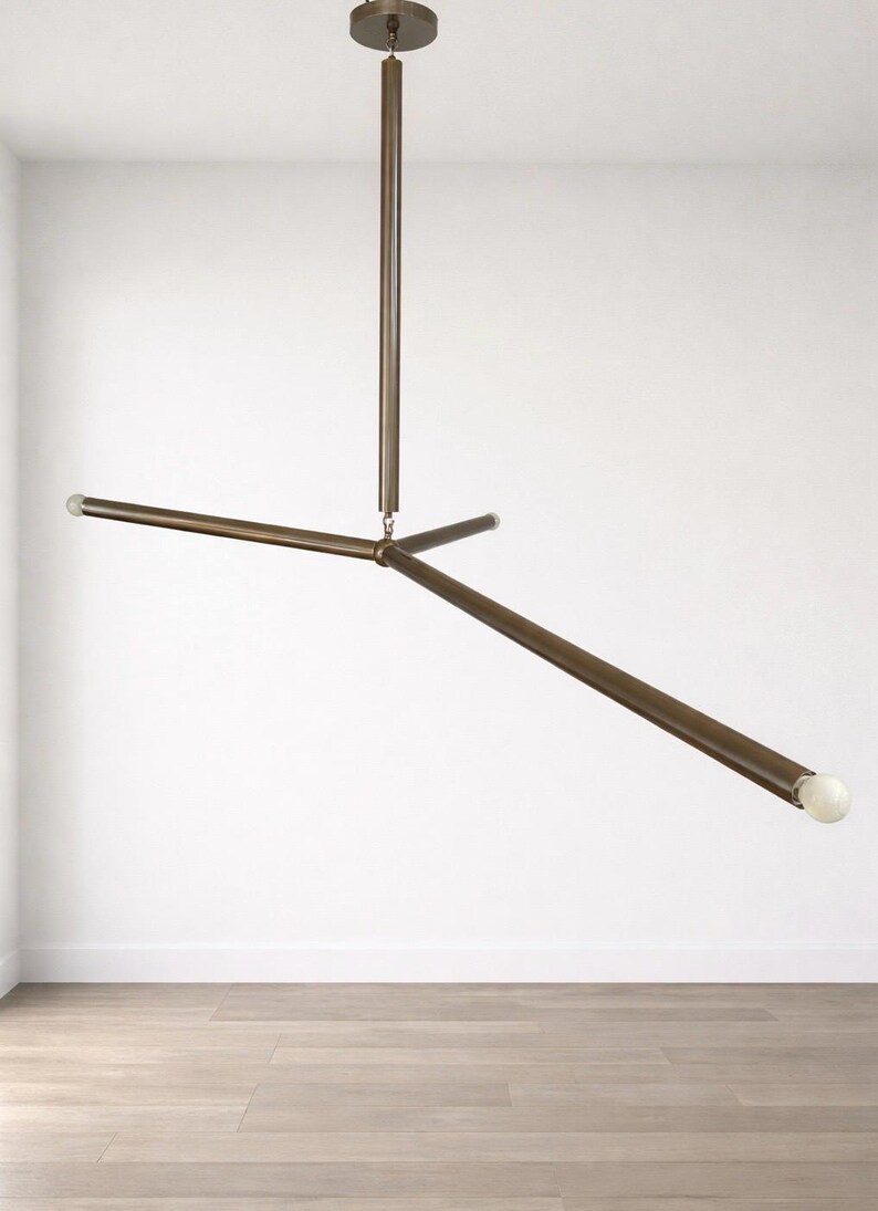 May include: A contemporary bronze ceiling light. The fixture has a central vertical rod and three horizontal rods extending outwards, each with a small, spherical light at the end. The light is suspended from the ceiling. The overall design is minimalist.