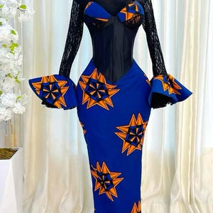 Könnte beinhalten: Ein blau-orange gemustertes Kleid mit schwarzem Oberteil und langen Ärmeln. Das Kleid hat einen herzförmigen Ausschnitt und eine taillierte Silhouette mit ausgestelltem Rock. Die Ärmel sind aus schwarzer Spitze, und das Kleid wird auf einer Schaufenquin präsentiert.