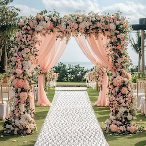 May include: A white lace aisle runner with a floral pattern, laid out in front of a wedding arch decorated with pink and white flowers.