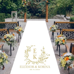 May include: White aisle runner with a gold floral design and the text "Eleanor & Korina 08.14.2024".