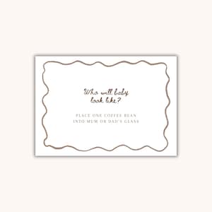 May include: A white card with a wavy brown border. The card features the text "Who will baby look like?" and "PLACE ONE COFFEE BEAN INTO MUM OR DAD'S GLASS" in brown script. The card is on a white background.