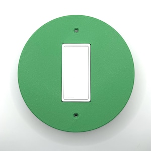May include: A round, green light switch cover with a white rectangular toggle switch.