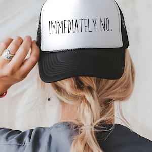 Puede incluir: Una gorra de camionero negra y blanca con un panel frontal blanco y una malla negra en la parte posterior. El panel frontal tiene el texto "IMMEDIATELY NO." impreso en negro.
