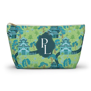 May include: A zipped pouch featuring a light green background with a repeating pattern of blue pagodas, trees, and winding paths. Centred on the front is a dark teal scalloped emblem containing the white capital letters P and L.