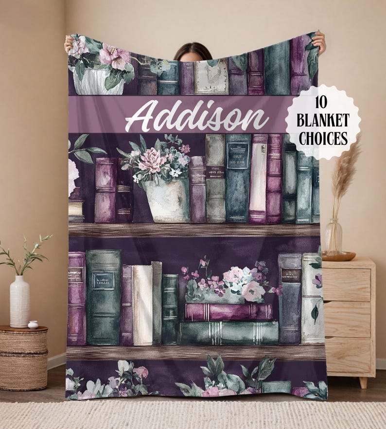 May include: A personalized blanket featuring a watercolor design of a bookshelf filled with books and floral arrangements. The name "Addison" is displayed prominently. The blanket has a purple and white color scheme, with the text "10 BLANKET CHOICES".