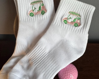Meias brancas até o tornozelo com bordado de carrinho de golfe rosa e verde.