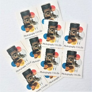 May include: Nine vintage United States postage stamps featuring a black and silver camera with a red, yellow, and blue background. The stamps are all 15 cents and say "Photography USA 15c".
