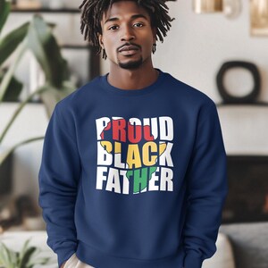May include: Navy blue sweatshirt with the text "PROUD BLACK FATHER" in white, red, yellow, and green. The sweatshirt is a crew neck style and is made of a soft material.