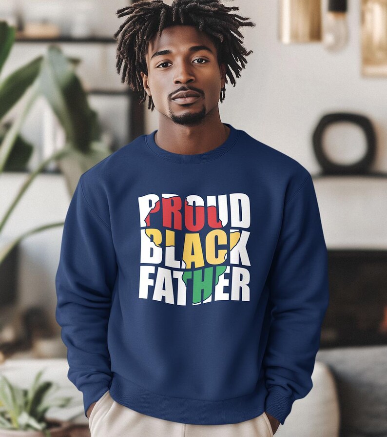 May include: Navy blue sweatshirt with the text "PROUD BLACK FATHER" in white, red, yellow, and green. The sweatshirt is a crew neck style and is made of a soft material.