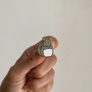 Mehoi Grey Chinchilla Hard Enamel Pin close up shown in hand with neutral backdrop