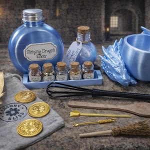 A blue-themed dragon potion kit displayed on stone, featuring a large round elixir bottle, a blue dragon cauldron, five tiny ingredient bottles, and assorted toy spellcasting tools.