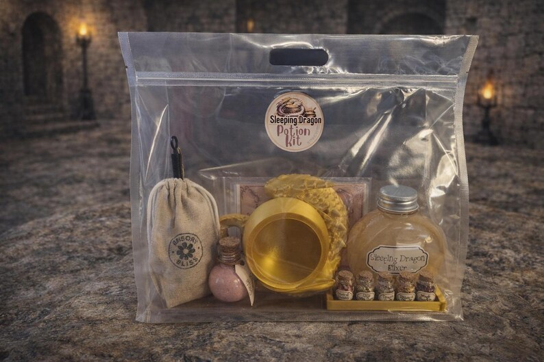 A clear plastic zipper bag containing a gold sleeping dragon potion kit with a cauldron, bottled elixir, and mini jars sitting on a stone surface.
