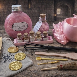A pink-themed sleeping dragon potion set featuring a large bottle labeled Sleeping Dragon Elixir, a pink dragon-shaped cauldron, five small glass jars, and wooden and metal crafting tools.