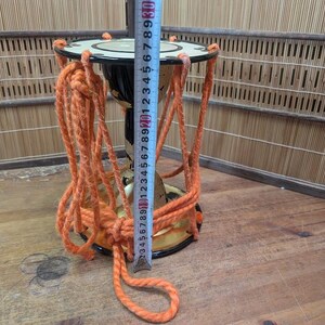 K&ouml;nnte beinhalten: Eine kleine, traditionelle japanische Trommel mit orangefarbenen Seilakzenten. Die Trommel ist schwarz und goldfarben, mit einer wei&szlig;en Oberseite. Ein Ma&szlig;band zeigt, dass die Trommel etwa 25 cm hoch ist.