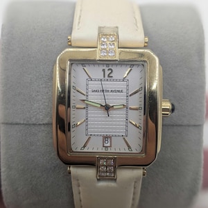 saks fifth avenue ladies tank watch all stainless steel construction. textured white face with date indicator. new battery tells time