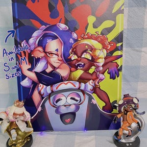 May include: A colorful artwork featuring two anime-style characters with vibrant hair and clothing. The background is a mix of red, blue, and yellow. Two figurines of the characters are on either side of the artwork. Text on the artwork says "Available in S and M Sizes."