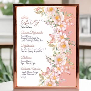 Könnte beinhalten: Eine gerahmte Getränkekarte für eine "Mis XV" Feier. Die Speisekarte hat einen rosa Hintergrund mit floralen und Schmetterlingsakzenten. Die Speisekarte listet klassische Margarita-, Michelada-, Paloma- und Tequila Sunrise-Getränkerezepturen auf.
