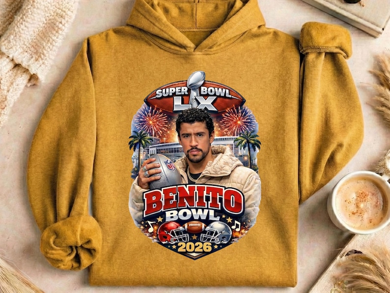 May include: Mustard yellow hoodie featuring a graphic of a man holding a football, with the text "Benito Bowl 2026" and "Super Bowl LX". The design includes football helmets, fireworks, and palm trees.