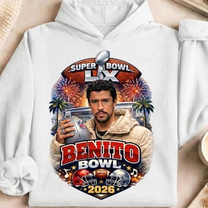 May include: White hoodie featuring a graphic of a man holding a football, with the text "BENITO BOWL 2026". The design includes footballs, helmets, and fireworks, with the words "SUPER BOWL LX" at the top.