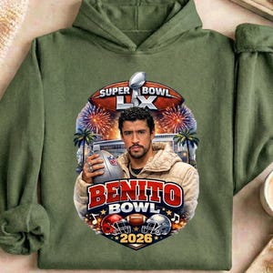May include: Olive green hoodie featuring a graphic of a man holding a football, with the text "Super Bowl LX" and "Benito Bowl 2026". The design includes football helmets, fireworks, and palm trees.