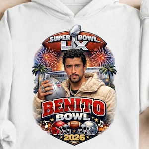 May include: White hoodie featuring a graphic of a man holding a football, with the text "SUPER BOWL LX" and "BENITO BOWL 2026". The design includes football helmets, fireworks, and palm trees.