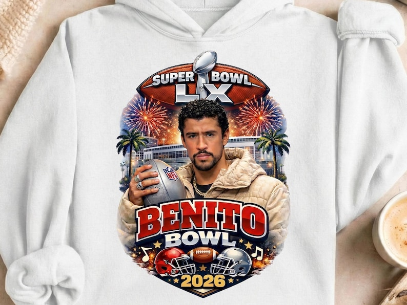 May include: White hoodie featuring a graphic of a man holding a football, with the text "SUPER BOWL LX" and "BENITO BOWL 2026". The design includes football helmets, fireworks, and palm trees.