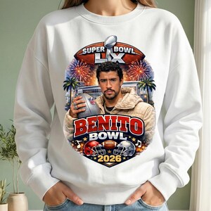 May include: White sweatshirt featuring a graphic of a man holding a football, with the text "Super Bowl LX" and "Benito Bowl 2026". The design includes football helmets, fireworks, and palm trees.