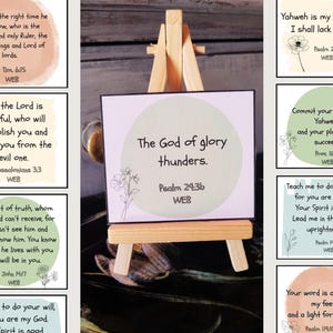 May include: A set of eight inspirational cards with bible verses printed on them. The cards are decorated with watercolour backgrounds and floral illustrations. The cards are displayed on a small wooden easel.