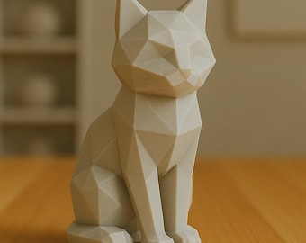 Op de afbeelding: Een geometrische kattenbeeld in een zittende positie. De sculptuur is lichtbeige van kleur en heeft een facetontwerp, wat het een moderne, minimalistische uitstraling geeft. De kat heeft spitse oren en een gedetailleerd gezicht.