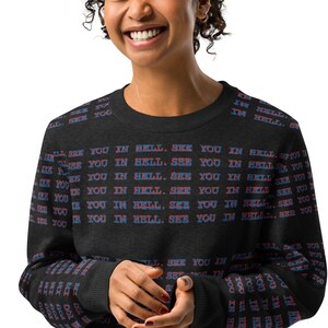 May include: A black long-sleeve sweatshirt featuring a repeating pattern of the text "SEE YOU IN HELL." printed in blue and red letters across the front and sleeves. The garment has a crew neckline and ribbed cuffs on the long sleeves.