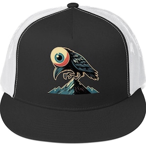 Può includere: Un cappello da camionista nero e bianco con una rete sul retro. La parte anteriore del cappello presenta una grafica di un corvo nero con un grande occhio su una montagna.